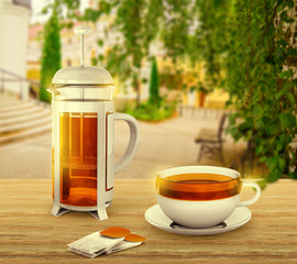 Black tea bags with cup and french press on background