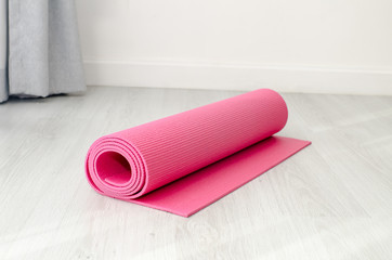 Pink yoga mat on gray floor at home.  Health concept.