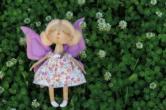 Little delicate handmade textile doll girl butterfly with closed eyes white hair and purple wings