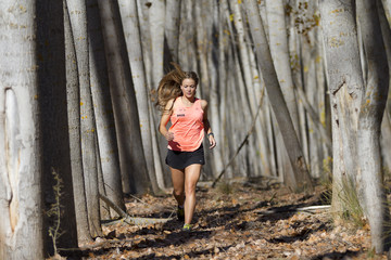 Mujer atleta corriendo en un bosque otoñal