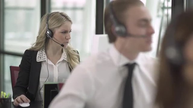 Professional in modern call center using headset and keyboard