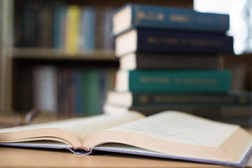 Opened Book and a Stack of Books on the Background