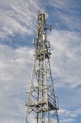 Telecommunication tower against cloudy sky