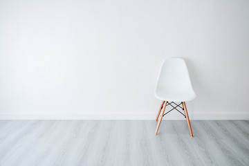 Conceptual Empty White Wooden Leg Chairs with white wall and gra