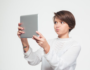Amusing woman making funny face and taking selfie with tablet