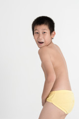 Asian shy boy with underwear on gray background.