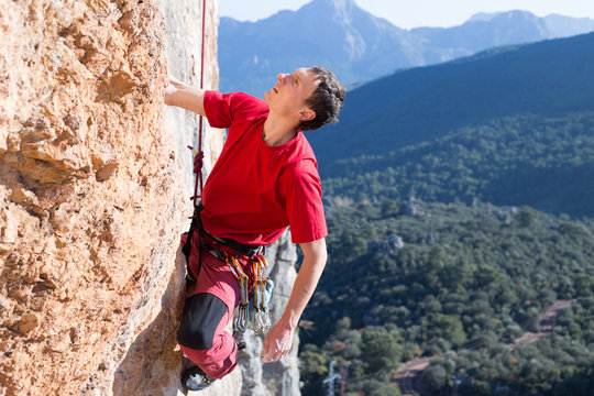 Young male climber hanging by a cliff