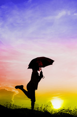 Motion blur jumping Umbrella girl with sunset silhouette