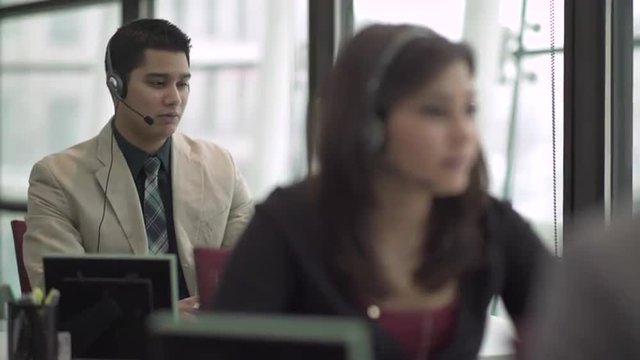 Professional in modern call center using headset and keyboard