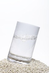 Trinkglas gefüllt mit frischem Mineralwasser auf groben Sandkörnern