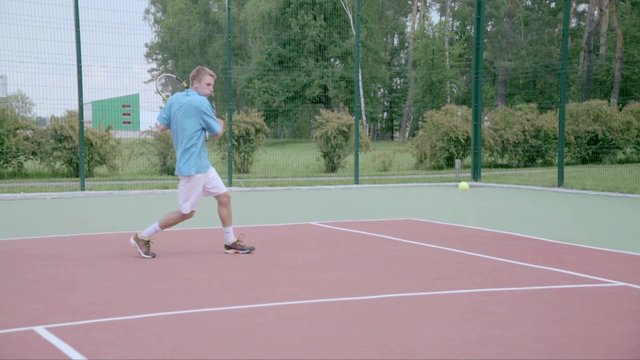 Tennis player uses backhand slice on the half court. Slow motion