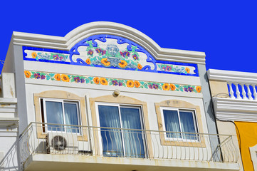 Floral tiles on the front of a house with a balcony in Loule