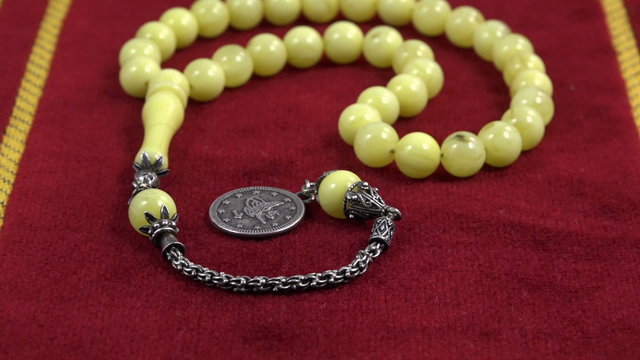 Islamic prayer beads made of amber over prayer rug under studio lighting. Three scenes.