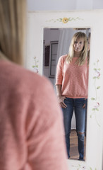 blonde Frau steht vor einem Spiegel
