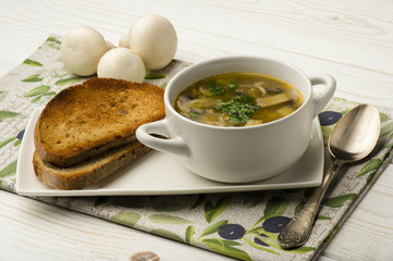 Mushroom soup with roasted bread on the wooden background.