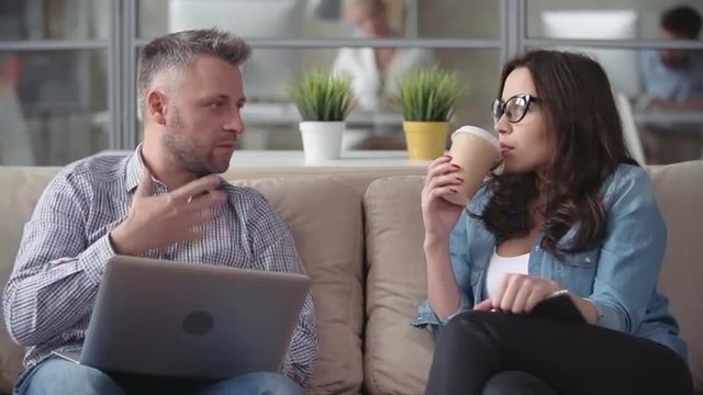 Man telling his female colleague funny jokes at coffee break