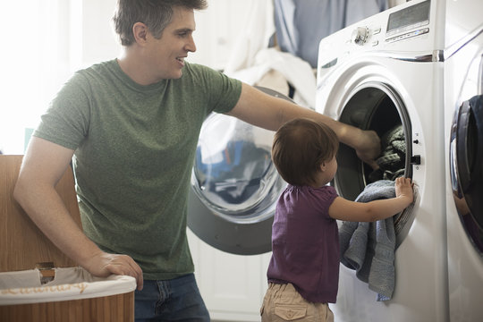 Father and daughter removing laundry from washing machine