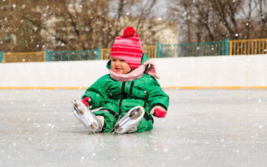 Fototapeta na wymiar cute little girl sitting on ice with skates
