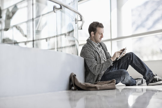 A man sitting down using a digital tablet. 
