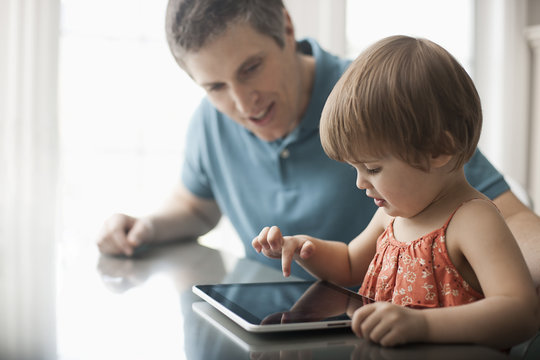 A father and daughter using a digital tablet