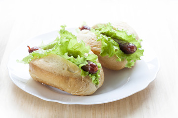 Hot dog. Grilled hot dogs with fresh salad lettuce on wooden table.