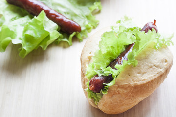 Hot dog. Grilled hot dogs with fresh salad lettuce on wooden table.