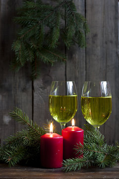 Christmas candles and lights. Two burning candles in with baubles and fir branch over wooden background, still life