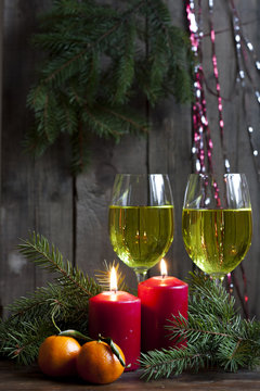 Christmas candles and lights. Two burning candles in with baubles and fir branch over wooden background, still life