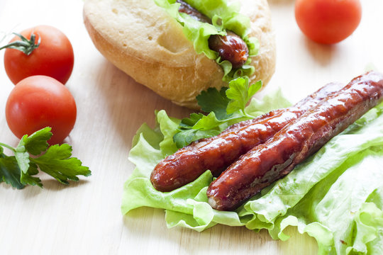 Hot dog. Grilled hot dogs with fresh salad lettuce on wooden table.