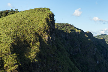 Peak of mountain with green grass field with clear blue sky, Thailand