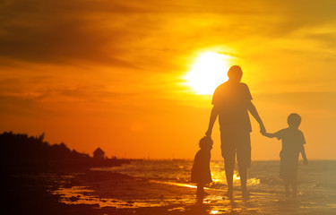 father and two kids walking at sunset