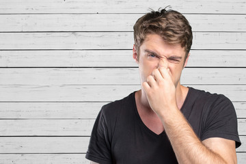 Young Man holding his nose against a bad smell