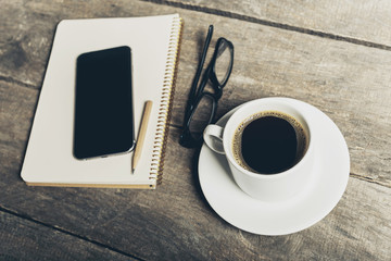 Fototapeta na wymiar Smart phone with notebook and cup of strong coffee