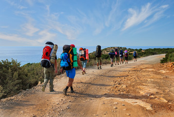 group of tourists with large backpacks are on road sea