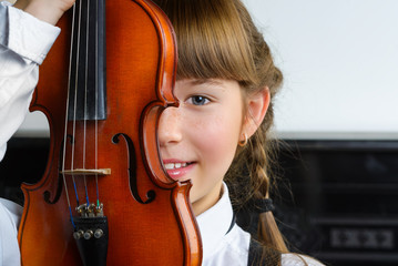 Cute little girl holding a violin indoor