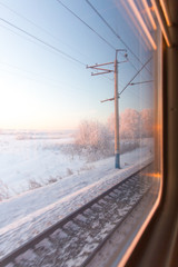 frozen pink sunrise in winter forest through the window of the train