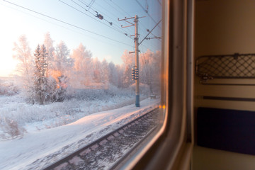 pink sunrise in winter forest through the window of the train