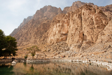 Obraz premium Mountains and clean water lake in beautiful persian valley with historical rocky reliefs in Bisotun