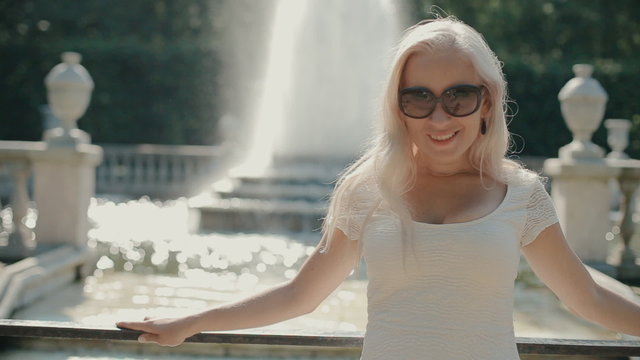 Happy blonde woman walking near the fountain