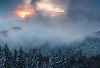 Colorful winter evening in the mountains at sunset. Dramatic overcast sky.