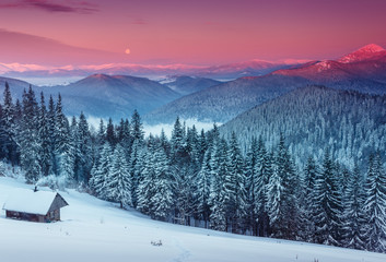 Colorful winter morning in the mountains. View of the moon and the snow-capped peaks.