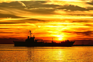 Obraz premium Bulk-carrier ship at sunset in the sea