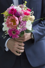 well-dressed man holding a bouquet of flowers. Holidays and cele