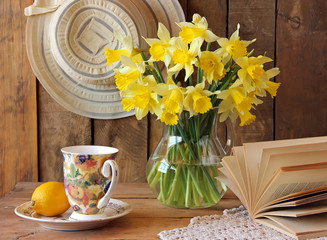 Still life with a bouquet of narcissuses in a transparent jug.
