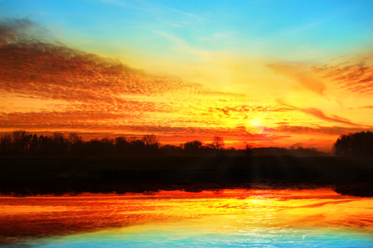 Kolorowy zachód słońca z odbiciem w jeziorze.