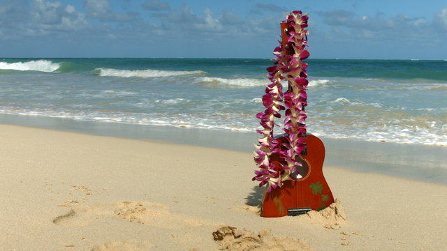 Hawaii concept with ukulele and Lei on beach. Traditional Hawaiian instrument and flower wreath or garland on perfect sandy beach on Oahu.