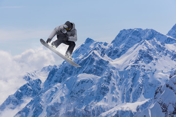 Flying snowboarder on mountains. Extreme sport.