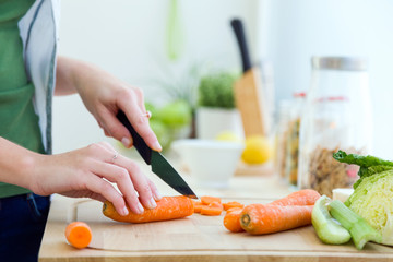 Pretty young woman cutting vegetables in the kitchen.
