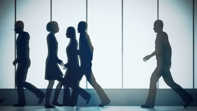 Silhouettes of a crowd of backlighted people walking in bright spacious lobby.