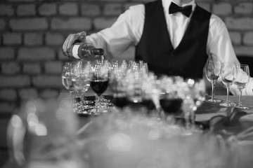 Mid section of a waiter pouring wine to serve a banquet table